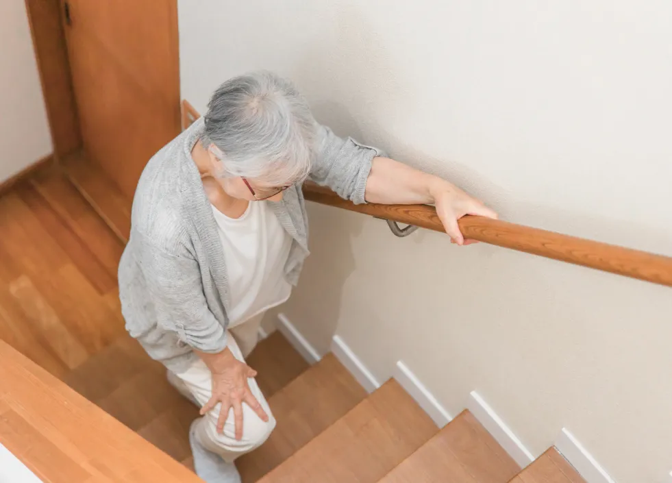 痛む膝で階段を上る女性