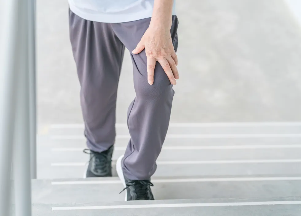 痛む膝で階段を上っている男性