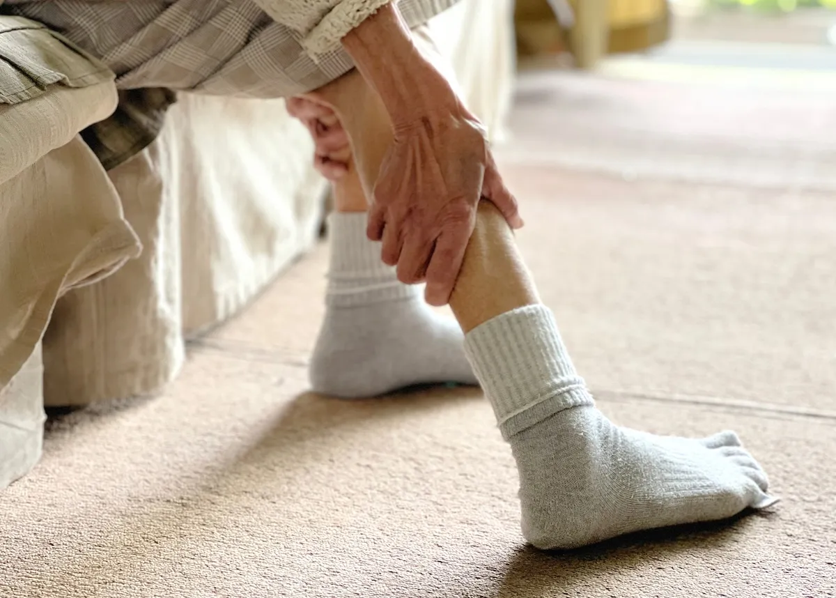 細い足首を触っている年配女性