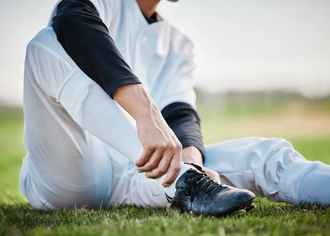 座り込んで靴の様子を見ている野球選手